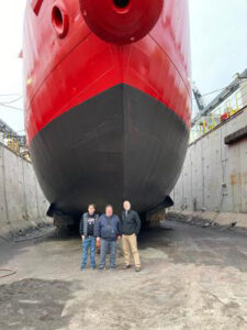 The Lightship in drydock in Vancouver. Left to right are CRMM staff members Aaron and Patrick, and Bruce Jones, Deputy Director of CRMM.